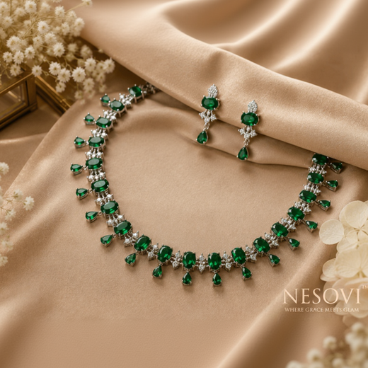 A luxury jewelry set featuring a necklace and matching drop earrings with emerald-cut green stones and clear accent stones.