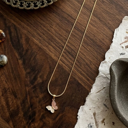 Gold necklace with a butterfly pendant on a wooden surface