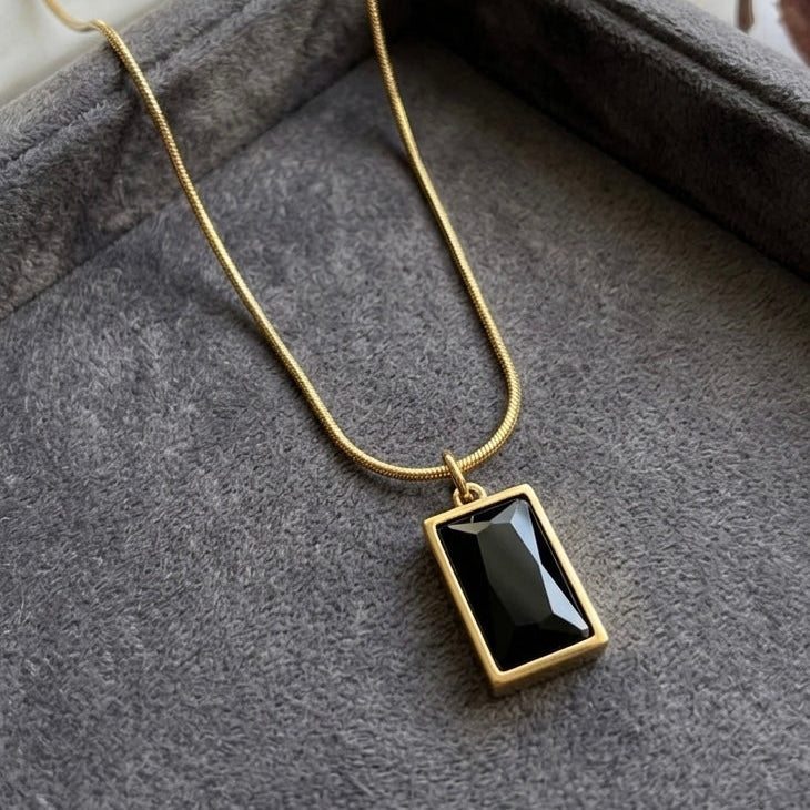 Necklace with a black pendant on a gray surface