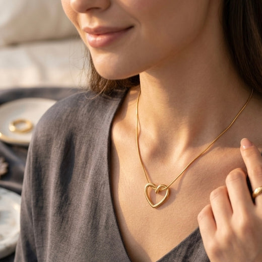 Woman wearing a gold necklace with a heart pendant, blurred background