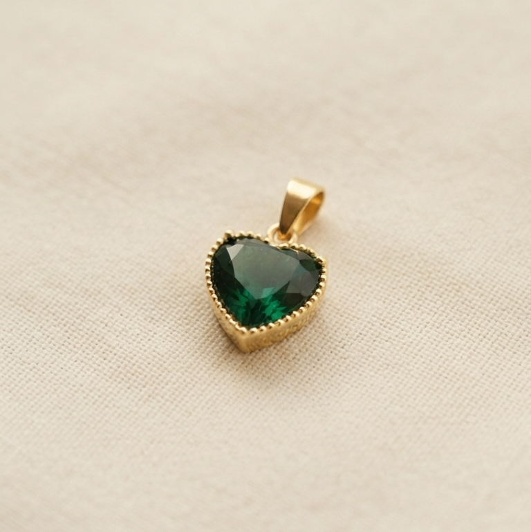 Heart shaped pendant with a green gemstone and a gold bezel