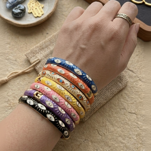 Hand wearing colorful bracelets on a wooden surface with jewelry and stones.