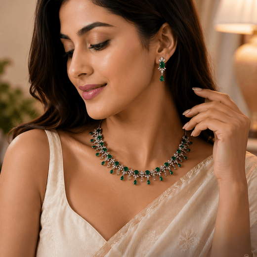 A woman wearing a green and silver gemstone necklace and matching drop earrings, styled with a cream-colored sari.